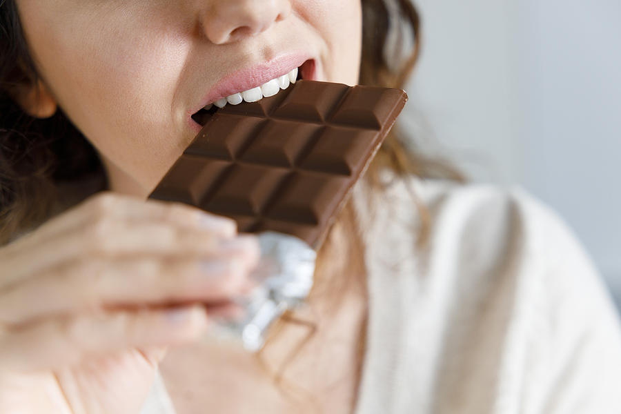Woman biting a chocolate bar #1 Photograph by Eternalcreative