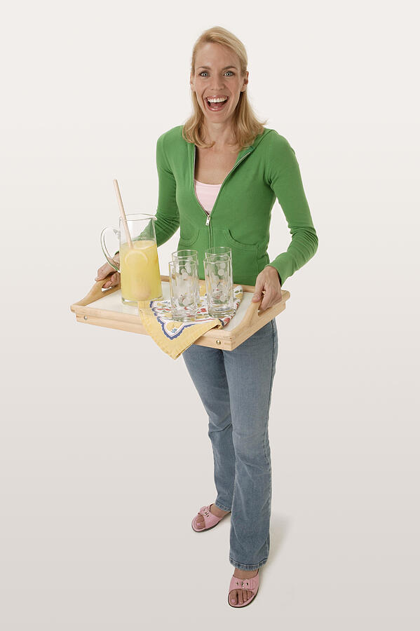 Woman carrying tray with lemonade #1 Photograph by Comstock Images