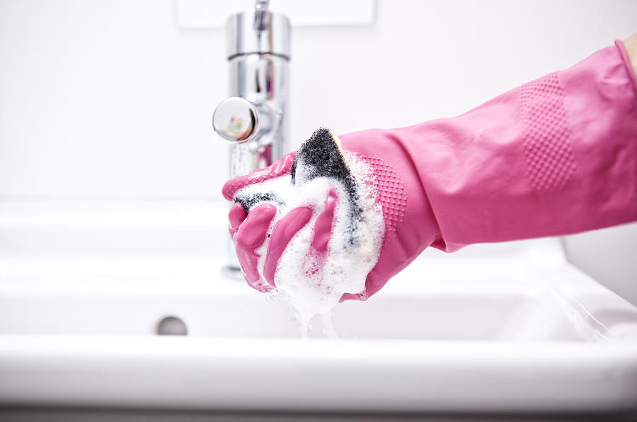 Woman cleaning bathroom sink with sponge #1 Photograph by Westend61