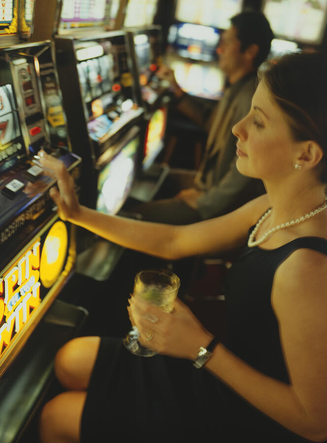 Woman gambling on slot machine in casino, side view #1 Photograph by Steve Mason