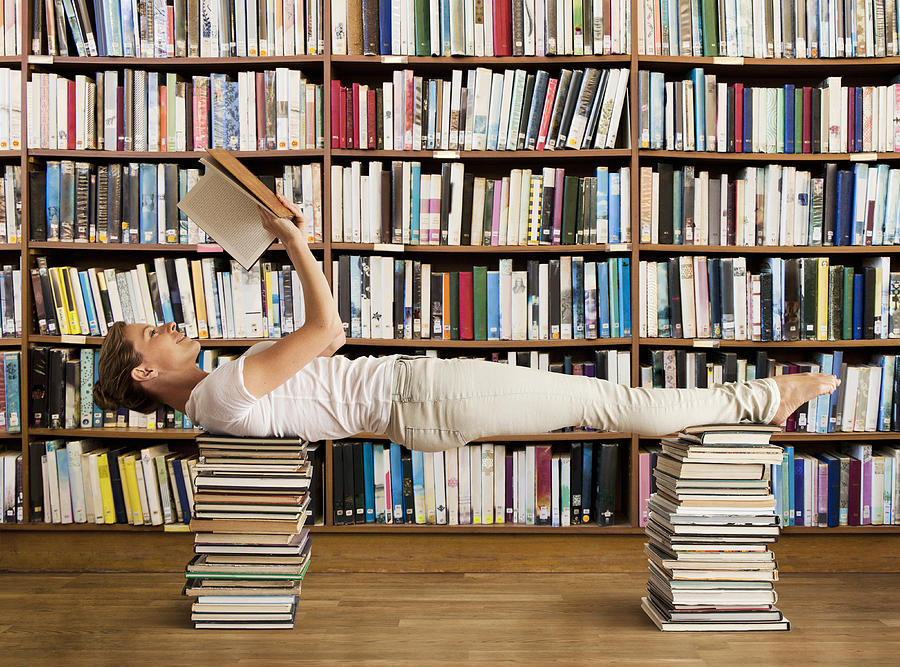Woman in library reads book and holds yoga pose #1 Photograph by Dimitri Otis