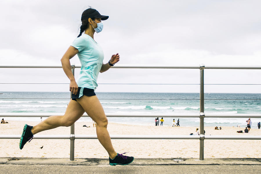Woman jogging wearing healthcare mask. #1 Photograph by Stevecoleimages