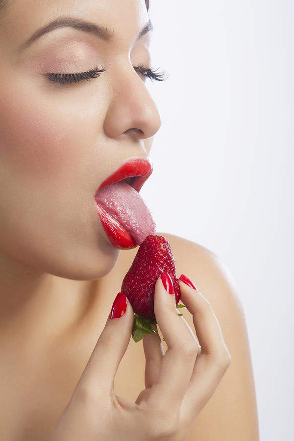 Woman licking a strawberry #1 Photograph by IndiaPix/IndiaPicture