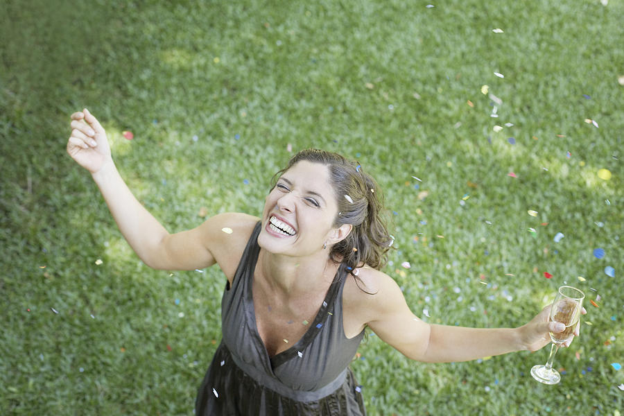 Woman outdoors standing on grass with champagne and confetti smiling #1 Photograph by Sam Edwards