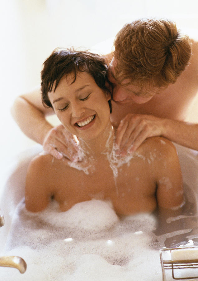 Woman taking bath, man massaging her shoulders #1 Photograph by John Dowland