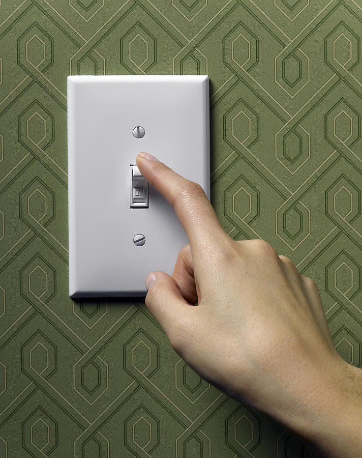 Woman turning off light switch on green wallpapered wall, close-up #1 Photograph by Jeffrey Hamilton