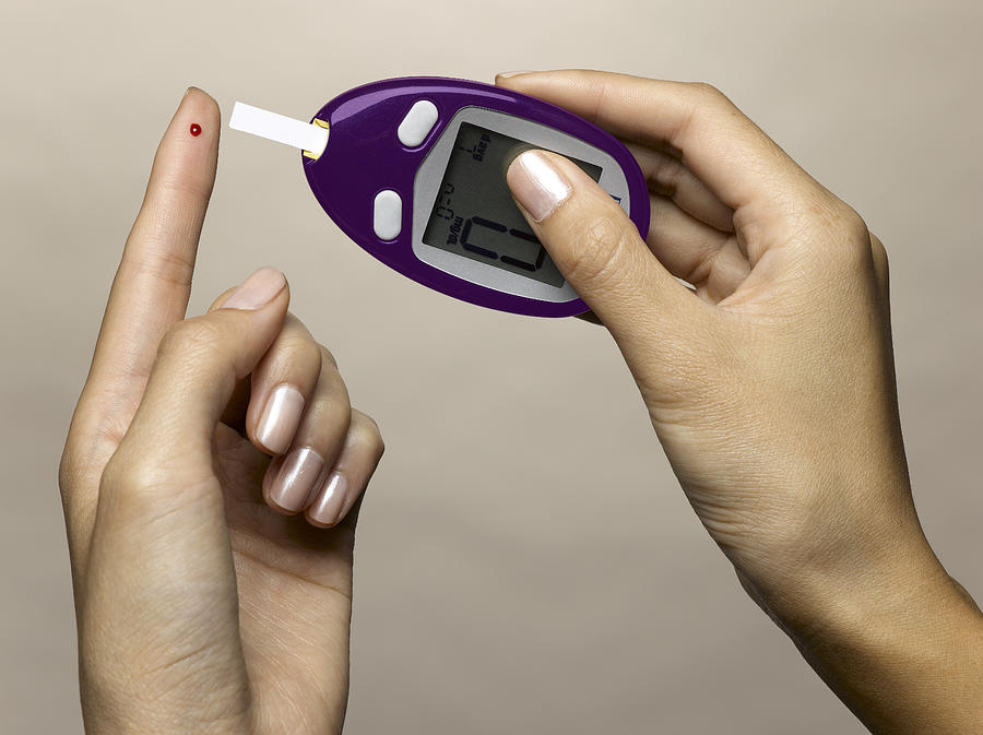 Woman using diabetes test kit #1 Photograph by Jeffrey Hamilton
