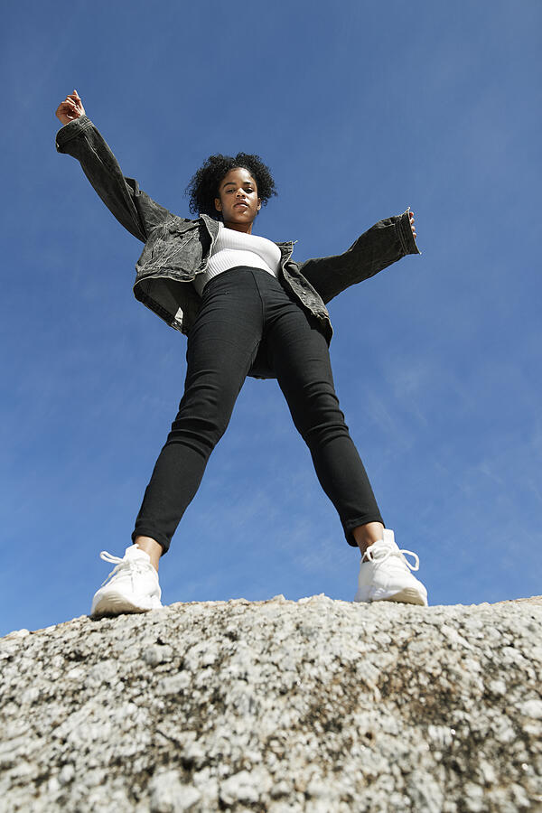 Woman wearing denim jacket on rock against blue sky #1 Photograph by Klaus Vedfelt