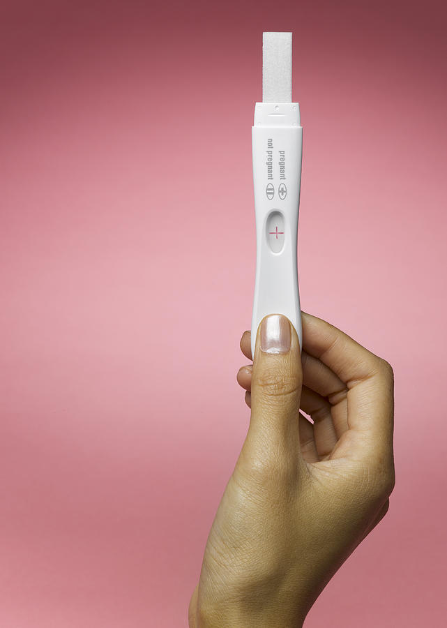 Womans hand holding pregnancy test #1 Photograph by Jeffrey Hamilton