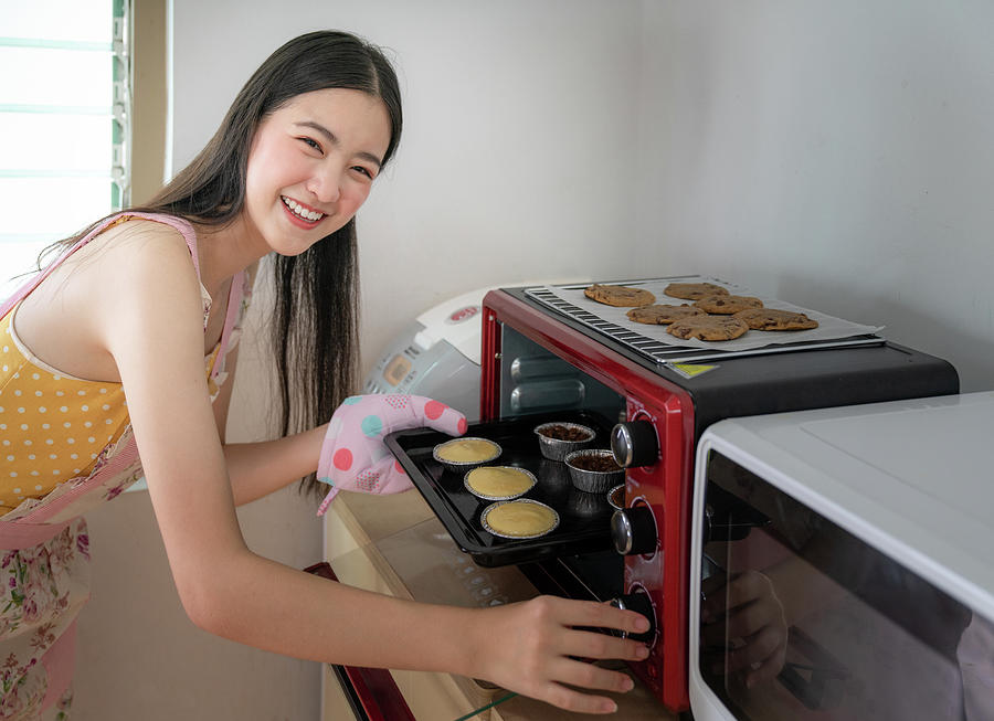 Young asian woman baking cookies in oven  #1 Photograph by Anek Suwannaphoom