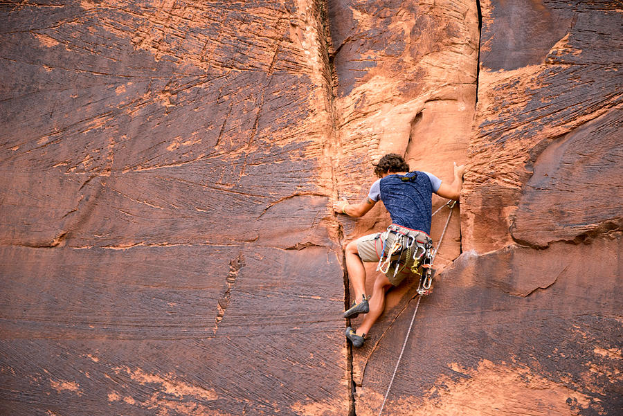 Young Caucasian Man Climbing a Sheer Cliff of Red Sandstone #1 Photograph by Grandriver