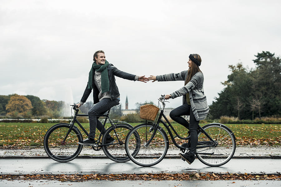 Young couple cycling on street #1 Photograph by Robin Skjoldborg