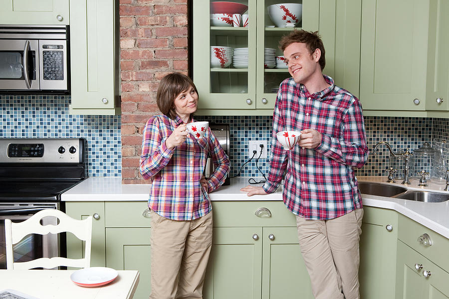 Young couple holding teacups in kitchen #1 Photograph by Image Source