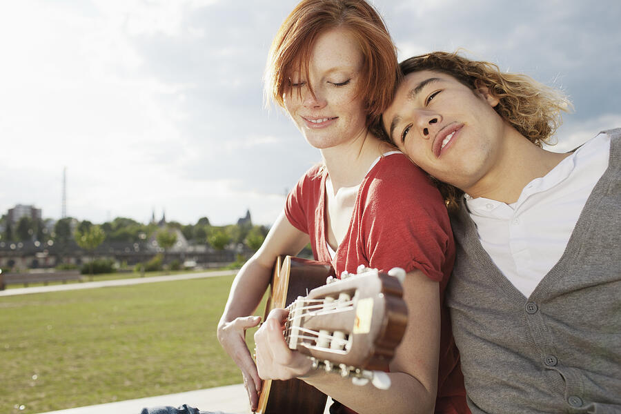 Young couple with guitar relaxing in park #1 Photograph by Oliver Rossi