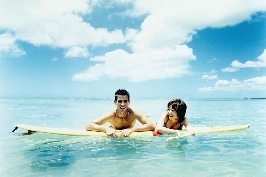 Young man and woman on surfboard in water #1 Photograph by Dex Image
