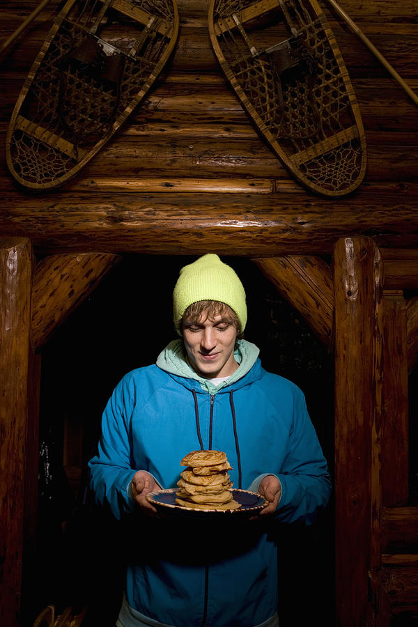 Young man holding plate of pancakes in log cabin #1 Photograph by Charles Gullung