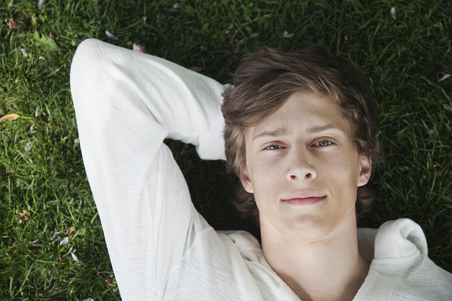 Young man lying in grass #1 Photograph by Oliver Rossi