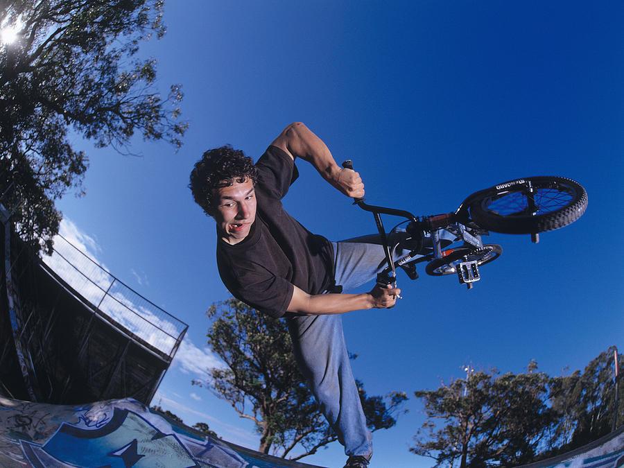 Young man performing bike stunt on ramp #1 Photograph by Dex Image