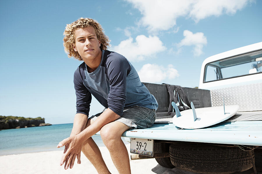 Young man sitting on trailer with surfboard #1 Photograph by Felix Wirth
