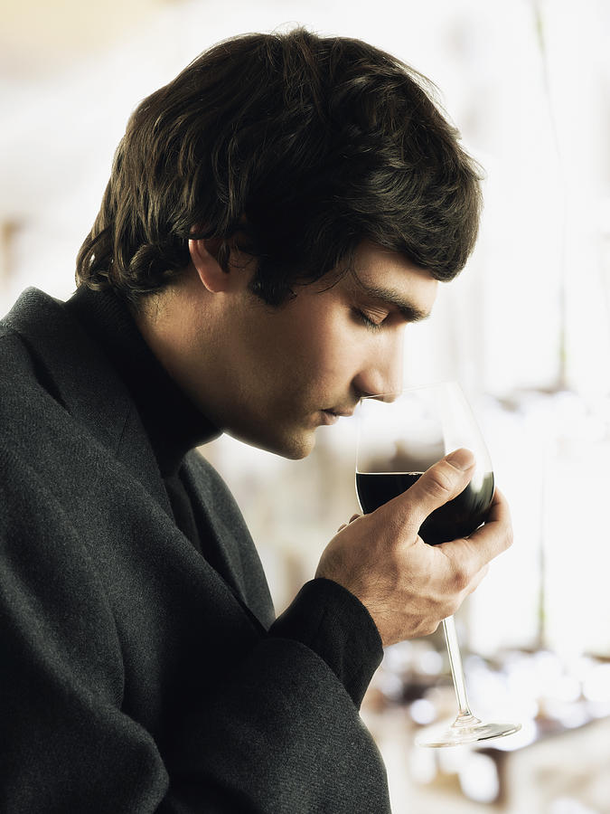 Young man sniffing glass of wine #1 Photograph by Colin Anderson Productions pty ltd