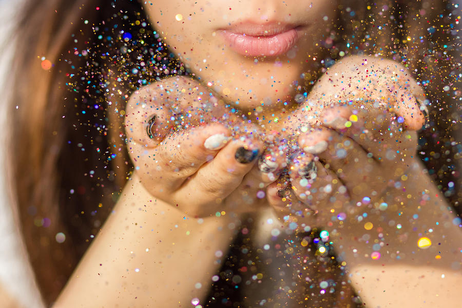 Young woman blowing colorful glitter in the air #1 Photograph by Owl Stories