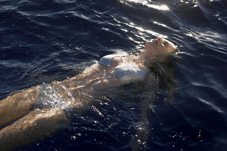 Young woman floating in swimming pool #1 Photograph by Felix Wirth