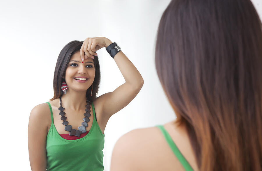 Young woman looking at herself in the mirror #1 Photograph by IndiaPix/IndiaPicture