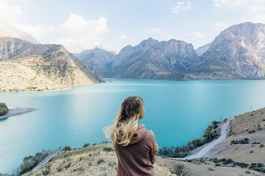 Young woman looks out across mountain lake #1 Photograph by Andrii Lutsyk/ Ascent Xmedia