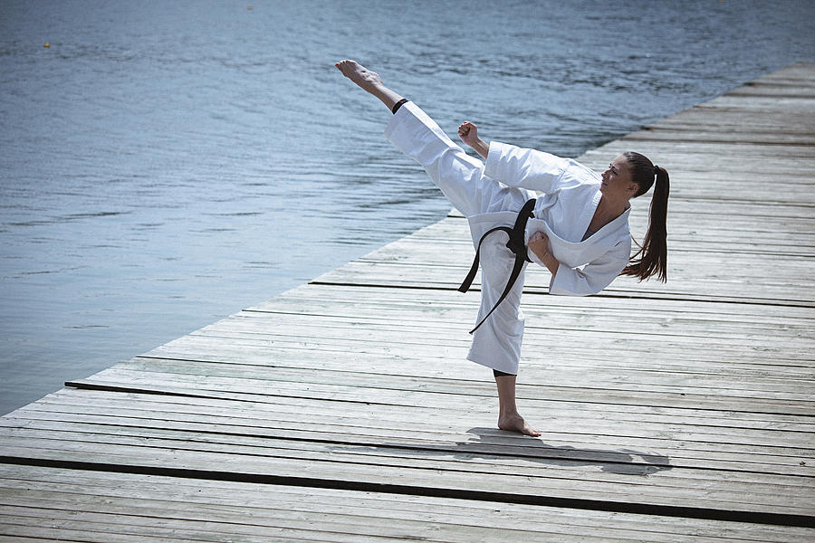 Young woman practising karate outdoors #1 Photograph by Gruizza