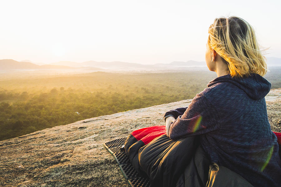 Young woman relaxes on rocky crest above jungle, sunrise #1 Photograph by Andrii Lutsyk/ Ascent Xmedia