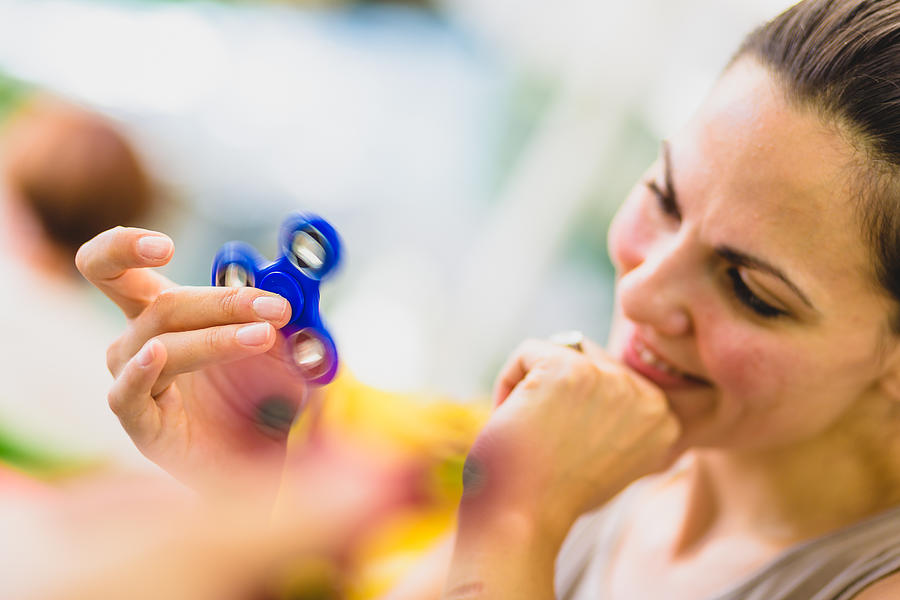 Young women is playing with fidget spinner in cafe. #1 Photograph by NoSystem images