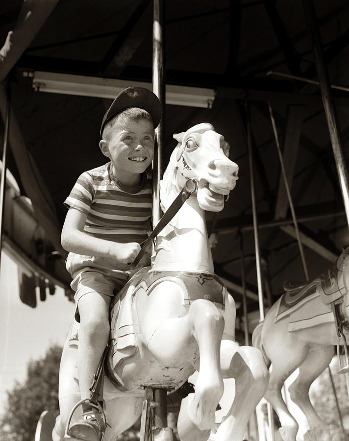 1940s 1950s Eager Smiling Boy Wearing Ball Cap And Striped T-shirt Riding On Carved Wooden Carousel  Photograph by Panoramic Images