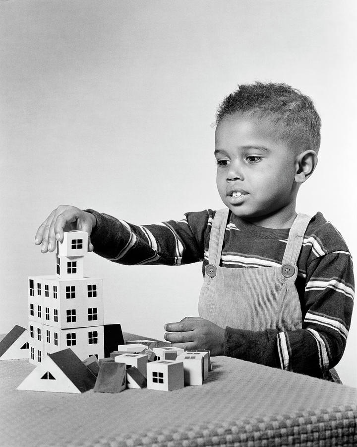 1950s engrossed African-American boy playing building constructing apartment house structure Photograph by Panoramic Images