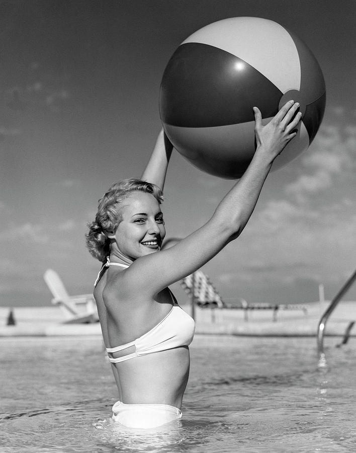 1950s Side View Of Blonde In White Bikini Standing In Pool In Waist-high Water Holding Beach Ball In Photograph by Panoramic Images
