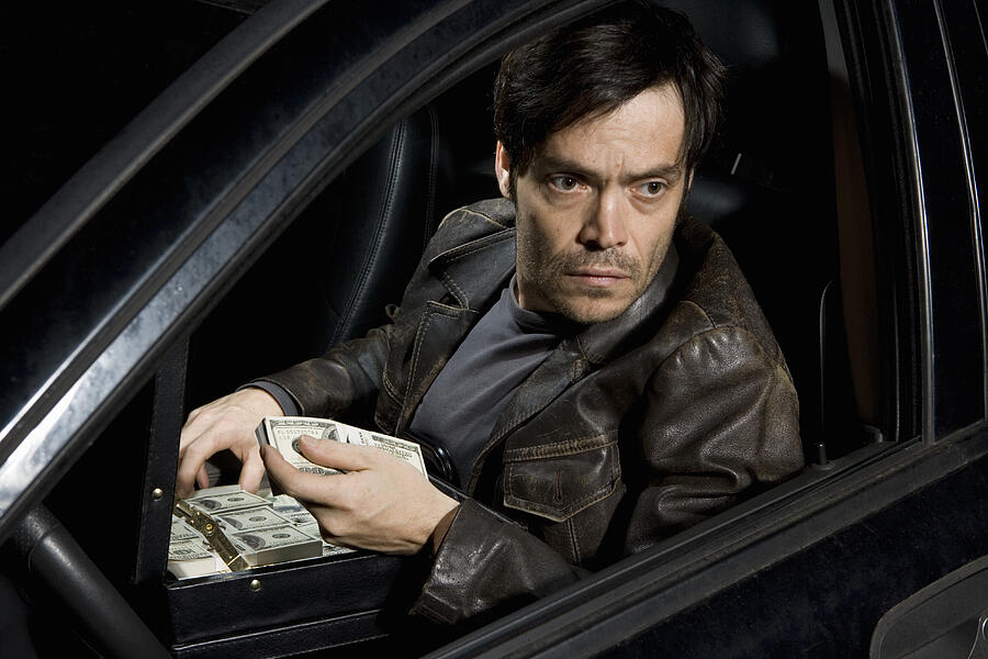 A man sitting in a car with an open briefcase full of money #2 Photograph by Marco Baass