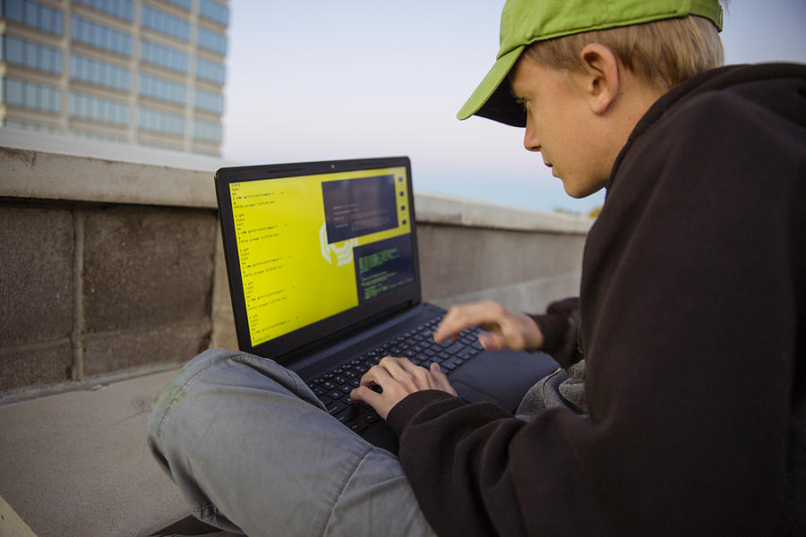 A teenage boy hacking with a laptop computer to commit cyber crime #2 Photograph by Robb Reece