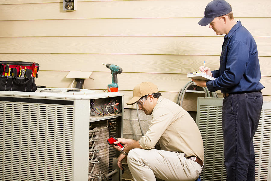 Air conditioner repairmen work on home unit. Blue collar workers. #2 Photograph by Fstop123