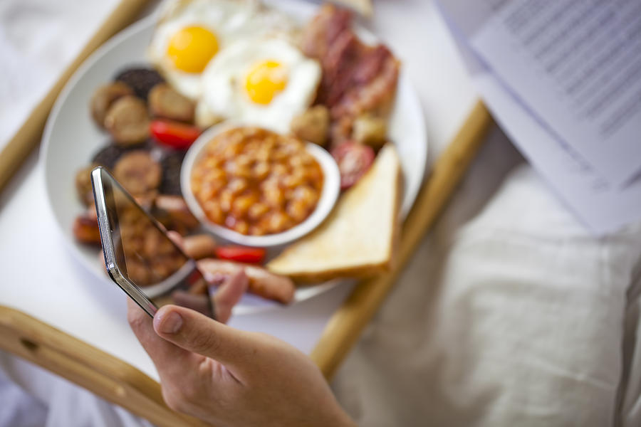 Businessman working in bed and eating  Irish breakfast on tray. #2 Photograph by Mikroman6