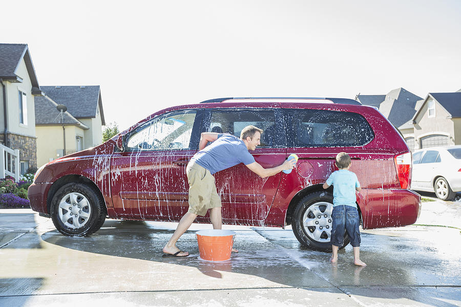 Caucasian father and son washing car in driveway #2 Photograph by Mike Kemp