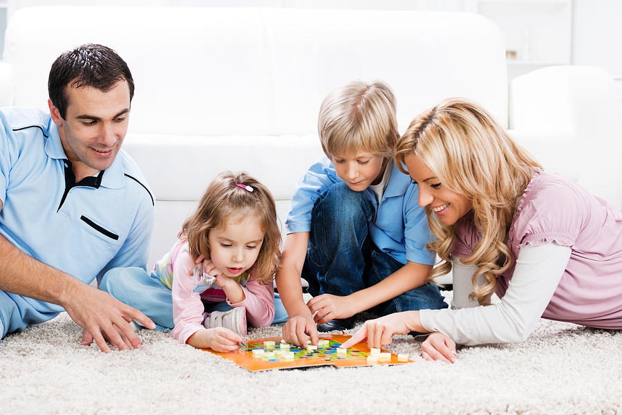 Cheerful parents playing board game with their children. #2 Photograph by Skynesher