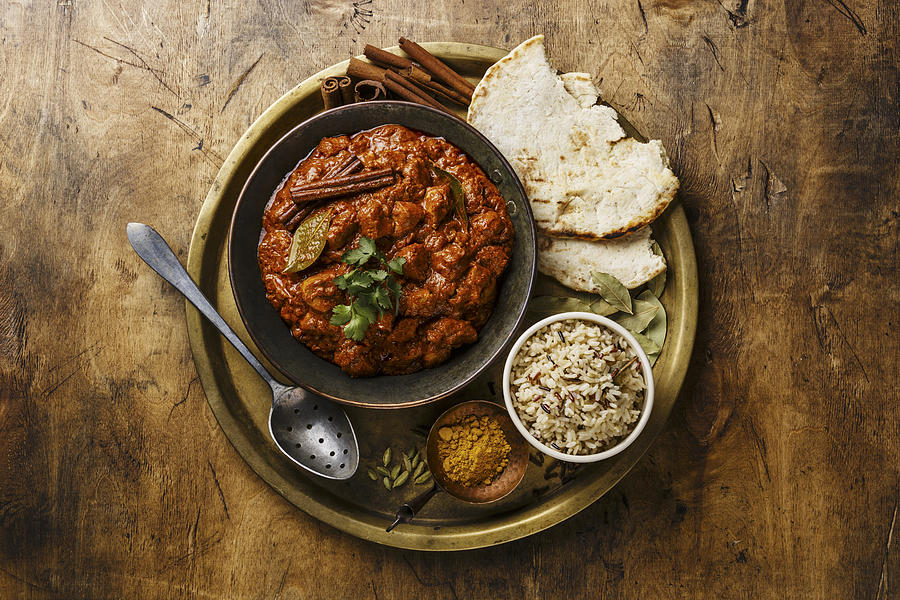 Chicken tikka masala spicy curry meat food in copper pan with rice and naan bread on wooden background #2 Photograph by The Picture Pantry
