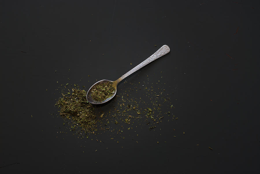 Dried basil on metal teaspoon on dark wooden table #2 Photograph by MichalDziedziak