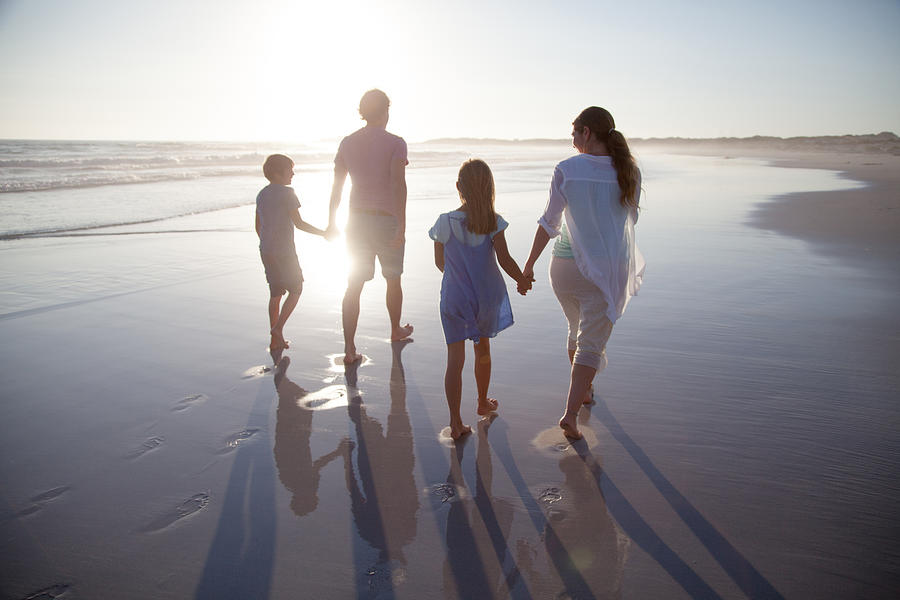 Family walking together on a beach #2 Photograph by Alistair Berg