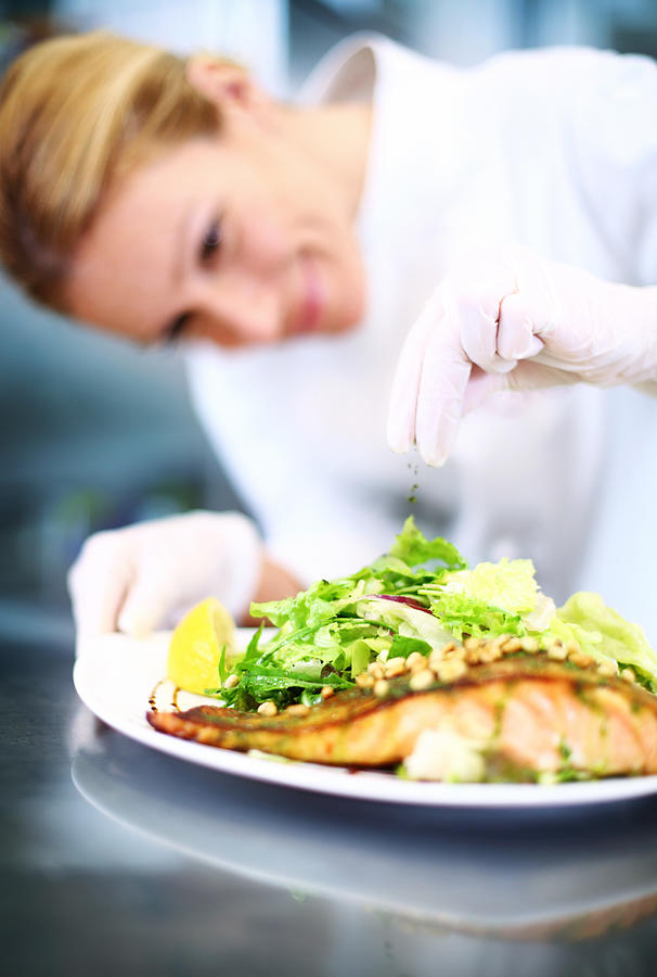 Female chef places finishing touches on meal. #2 Photograph by Gilaxia