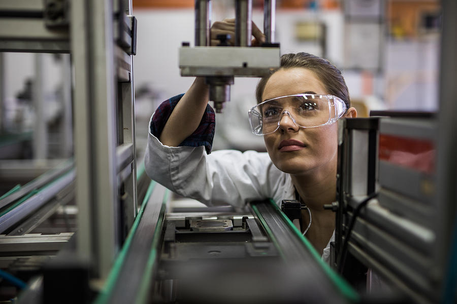 Female engineer examining machine part on a production line. #2 Photograph by Skynesher