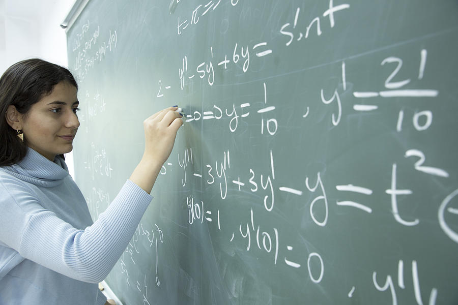 Female Student writing mathematical formula in front of the blackboard #2 Photograph by Leventince