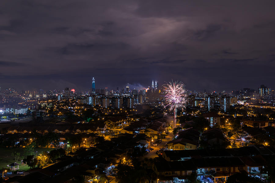 Fireworks explode near Malaysias landmark Petronas Twin Towers and residential area during New Year celebrations in Kuala Lumpur. #2 Photograph by Shaifulzamri