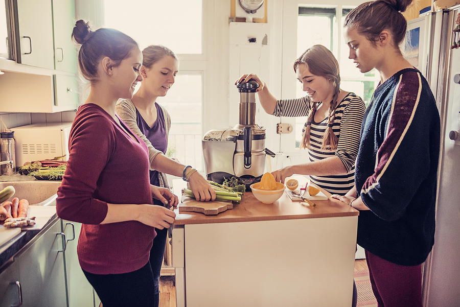 Four roommates using a juicer in their appartement kitchen. #2 Photograph by Martinedoucet