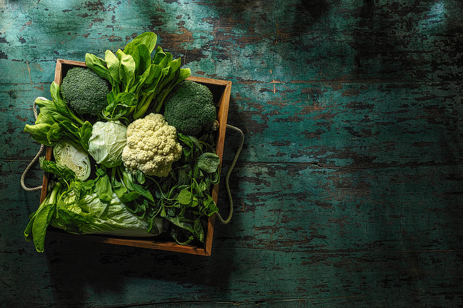 Fresh green leaf vegetables in an old wooden crate on an old wooden turquoise table. #2 Photograph by Enviromantic