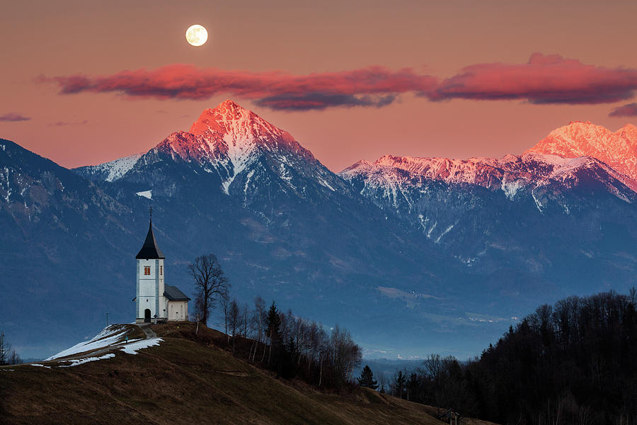 Full moon rising over Jamnik church and Storzic at sunset Photograph by Ian Middleton